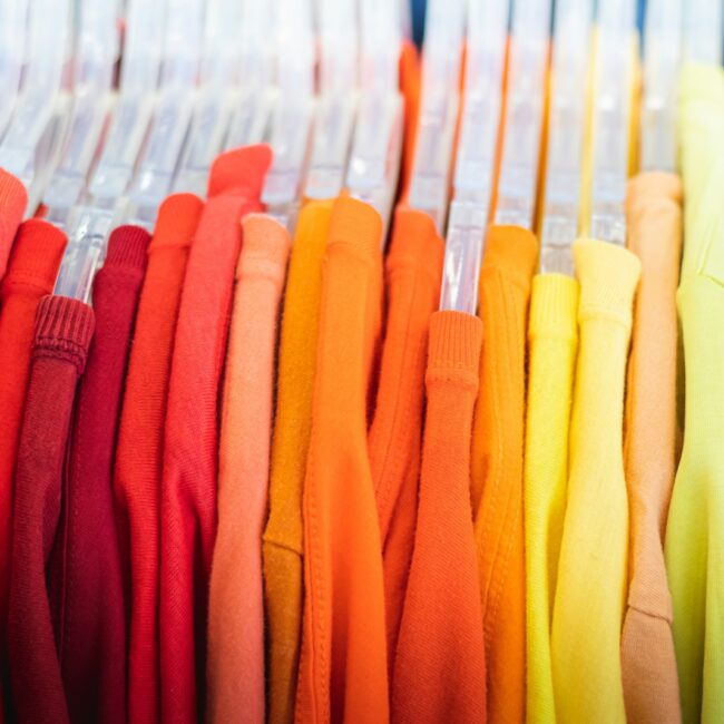 a bunch of different colored shirts hanging on a rack